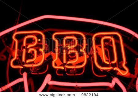 Røde neon tegn af ordet 'BBQ' inde omridset af en gris, på en sort baggrund.