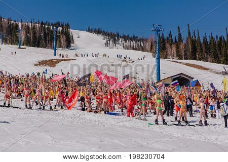 Group Of Young Happy Pretty Women On A Snowboard In Colorful Bikini With Flags.
