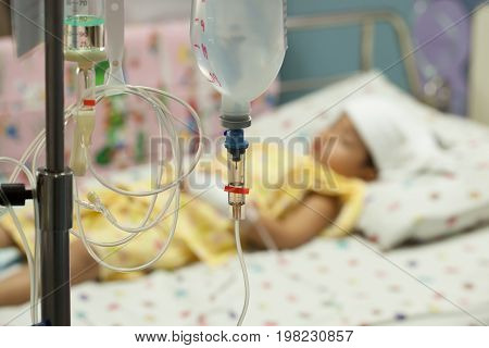 Close up saline IV drip for patient and Infusion pump in hospital In the hospital with a fragment of medical equipment and patients boy High fever for bacterial infections.