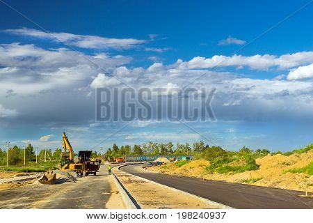 Crawler Excavator loads truck with rubble using bucket. Construction of high-speed bypass road around Krasnoe Selo Saint Petersburg. Heavy industrial machinery equipment for excavation works. Russia