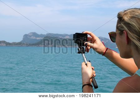 European girl tourists enjoy the GoPro camera and view of the island and the sea on the boat.