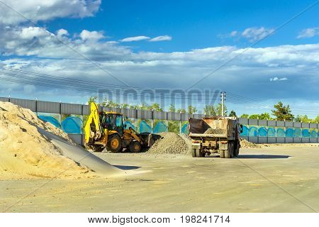 Heavy Tractor loads truck with rubble using bucket. Construction of high-speed bypass road around Krasnoe Selo Saint Petersburg. Heavy industrial machinery equipment for excavation works. Russia