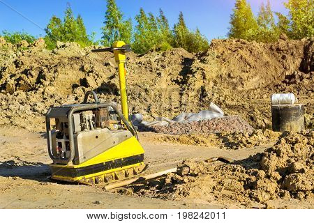 Manual ramming machine for compacting soil on construction of high-speed road around Krasnoe Selo Saint Petersburg. Light mechanized tools and equipment for works at industrial construction. Russia