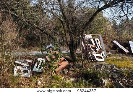 Old big letters of a sign store abandoned on grass