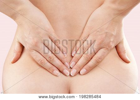 Beautiful woman touching lower back with both hands. Lower back pain.