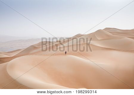 woman running down a dune in Rub al Khali Desert at the Empty Quarter in Abu Dhabi United Arab Emirates