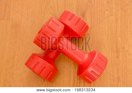 Two small pink dumbbells on wooden background.