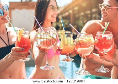 Group of friends in the swimming pool drink