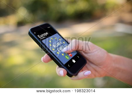 Roam free text and European Union flag on mobile display against cropped hands of woman using phone