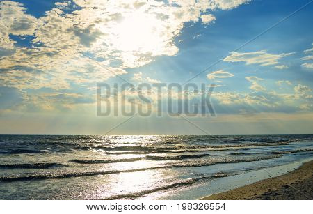 Beautiful sunset Black sea. Gold sea sunset landscape. The rays of the sun from behind the clouds. Black Sea foreland landscape. Regional Landscape Park of Kinburn Foreland. Green water surface, with sea waves and sandy shore. Kinburn Spit – a spit at the
