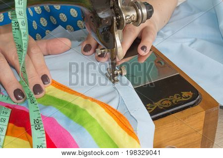 Woman hand on sewing machine.Dressmaker work on the sewing machine. Hobby sewing fabric as a small business concept. Female tailor threading leather material on sewing machine