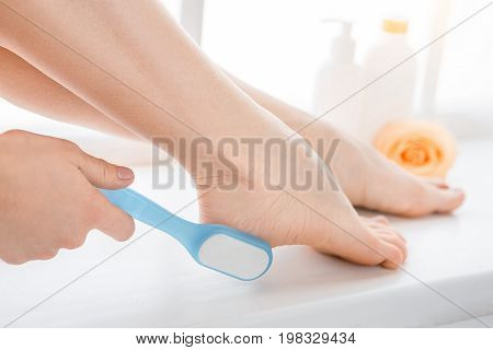 Young female body care at home using pumice