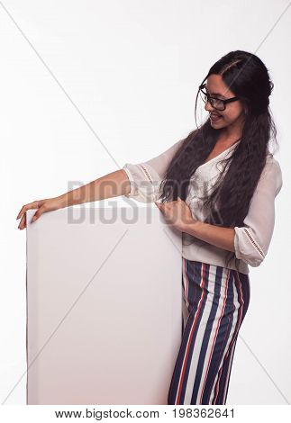 Young jocular woman portrait of a confident businesswoman showing presentation, pointing placard gray background. Ideal for banners, registration forms, presentation, landings, presenting concept.