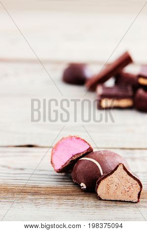 Some cut chocolate candies on wooden background.
