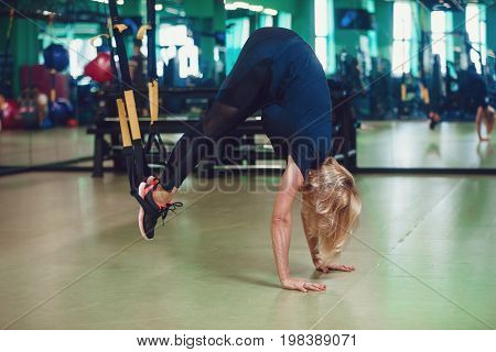 Core body exercise concept. Woman exercising with suspension straps in gym.