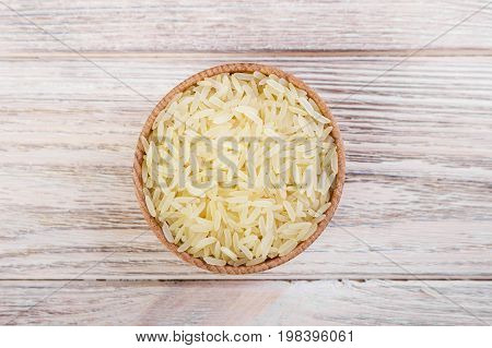 Wooden bowl full of basmati rice top view.