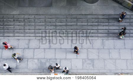 On street walk in top view man and woman with shopping bags walk on square block pedestrian street walk way with stair of the building (aerial city street view)