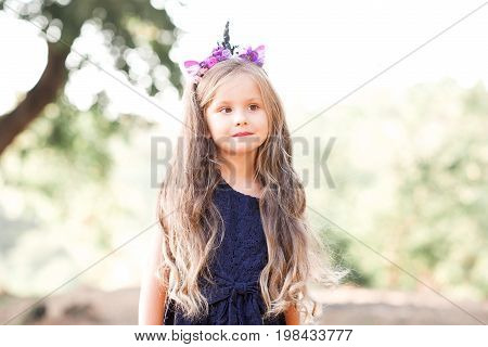 Cute baby girl 4-5 eyar old wearing dress and handmade headband outdoors. Looking away. Summer time.