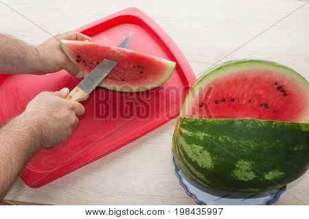 Men hand hold from on fresh watermelon cutting for eatin on table background. Male cutting a delicious sweet watermelon
