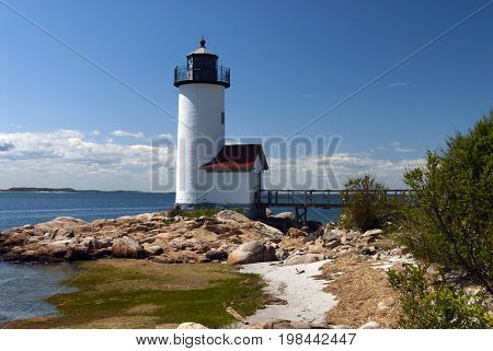 Annisquam lighthouse overlooks harbor on a sunny day in Massachusetts.