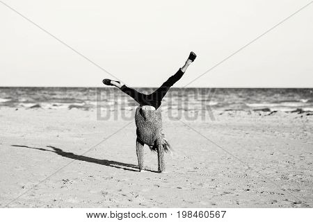 Black and white portrait of funny white Caucasian child kid teenager doing cartwheel playing on beach on sunset. Happy lifestyle childhood concept