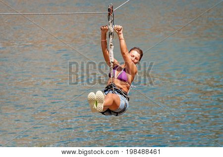 Ukraine Migea - July 30 2017: Zipline. The woman in the equipment slides on a steel cable. Trolley Track Over the lake. Extreme and active rest.