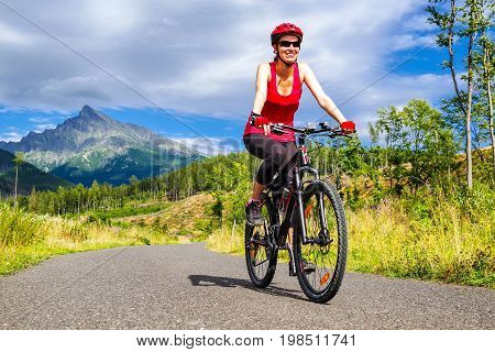 Happy woman on MTB bike on road in Ticha valley at High Tatras mountains Slovakia.