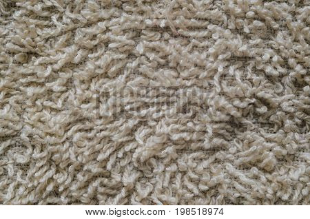 Macro shot of a beige color towel. Texture is similar to the texture of a fleecy knotted-pile carpet. Chaotic pattern of villi on fabric material.