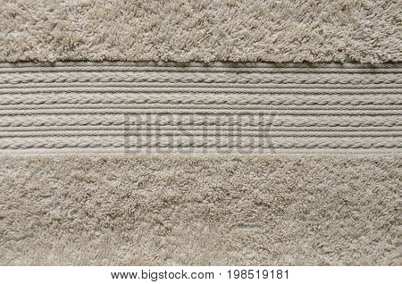 Element of beige color towel. Fleecy part and decorative element with braided pigtails. Texture is similar to the texture of a fleecy knotted-pile carpet.