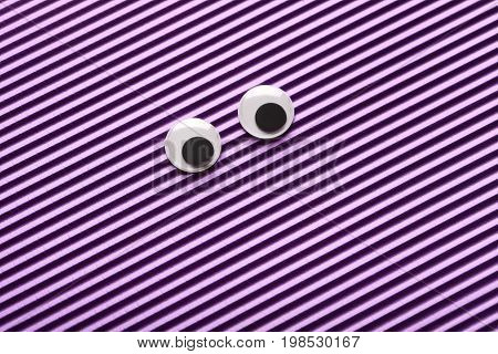 Googly eyes on the striped purple background