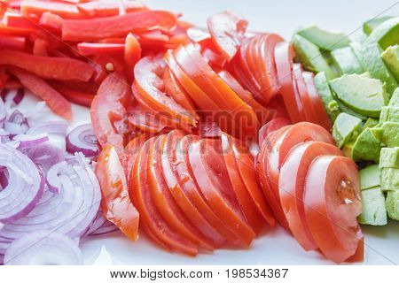 delicious piles of freshly sliced avacado tomato and onion on serving plate