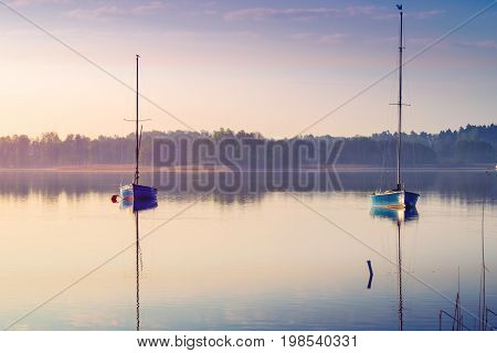 Yachts float on the calm waters of the lake. Early morning. Masuria Poland .