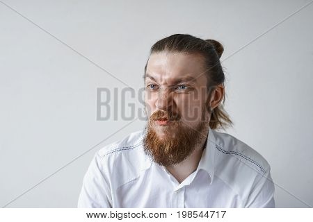 Picture of funny emotional young European office worker with facial hair grimacing screwing nose his look expressing dislike discontent or dissatisfaction. Negative human reaction and attitude