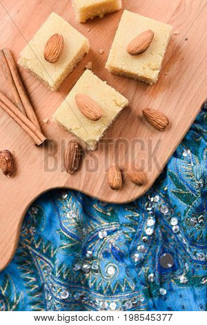 Indian traditional dessert halva made with flour and milk wih cinnamon and almonds served on embroidered blue cloth overhead view