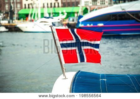 Norwegian flag flying in the wind over the sea on heavy foggy day in Northern Norway