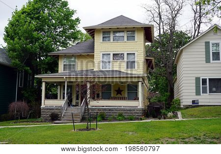 CADILLAC, MICHIGAN / UNITED STATES -  MAY 31, 2017: A yellow Victorian home with a wraparound front porch in Cadillac's Courthouse Hill Historic District.
