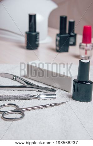 Manicure set for gel nail procedure - colored gel varnishes scissors tools cuticle remover and white file on white table