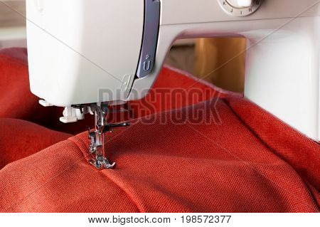 Close up of sewing machine working with red fabric