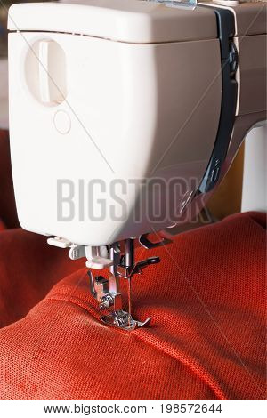 Close up of sewing machine working with red fabric
