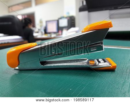 A stapler on table with blurred office background.
