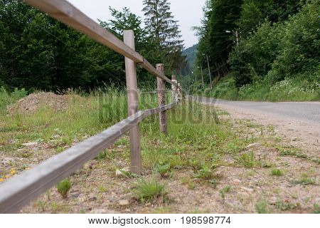 Against The Background Of The Wood Near The Road There Is A Wooden Protection