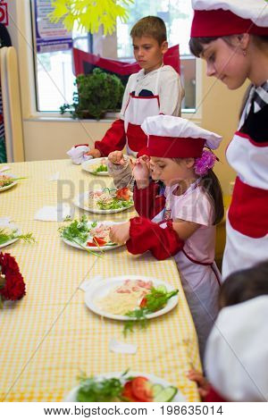 Alchevsk, Ukraine - July 30, 2017: School Cooks For Children. Learn To Cook Pasta With Sausages