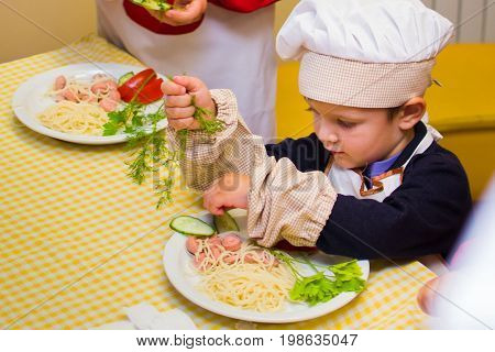 Alchevsk, Ukraine - July 30, 2017: School Cooks For Children. Learn To Cook Pasta With Sausages
