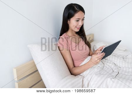 Woman using tablet computer on bed