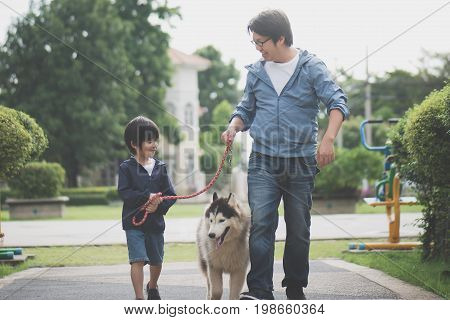 Asian Father And Son Walking With A Siberian Husky Don In The Park Under The Rain