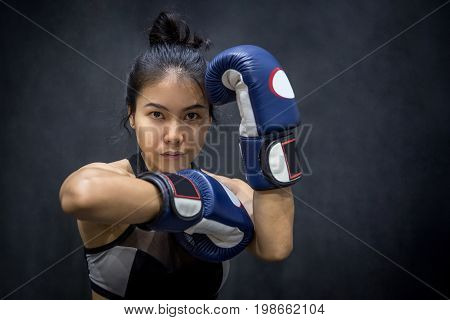 Beautiful young Asian woman posing with blue boxing gloves black background