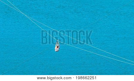 Zipline. The woman in the equipment slides on a steel cable. Trolley Track Over the lake. Extreme and active rest.