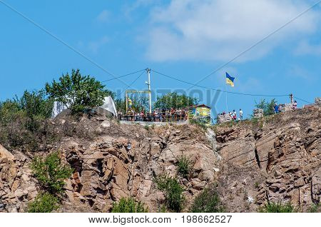 Ukraine Migea - July 30 2017: Zipline. Starting platform on a high rock. The man in the equipment slides on a steel cable. Trolley Track Over the lake. Extreme and active rest.