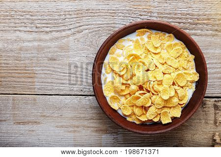 Cornflakes in a brown clay plate on a shabby wooden background space for text