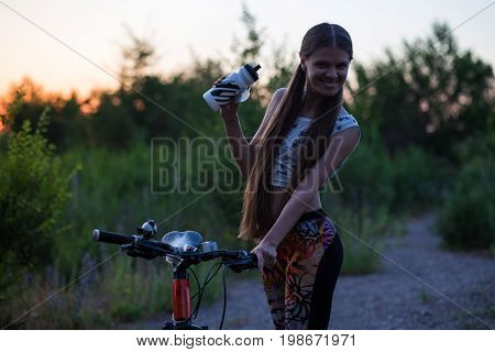 Attractive sporty girl with long hair on a bicycle on sunset